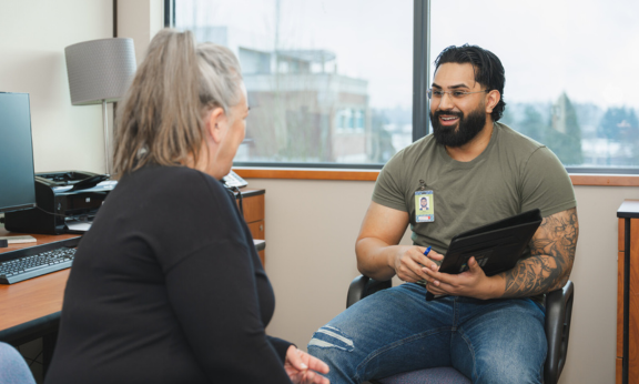 Mental health care worker speaking with a patient in an office.