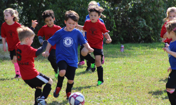 A group of kids playing soccer outdoor