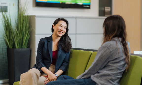 Two students sitting on a couch engaging in conversation.