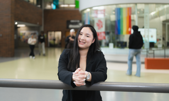 A student leaning on a railing in Douglas College building.