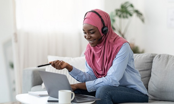 A student looking at her laptop and wearing headphones