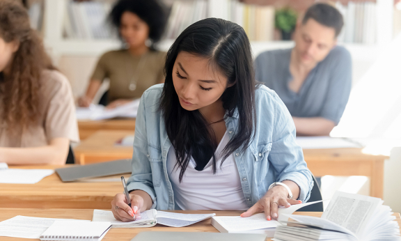 A student looking at her notebook and writing