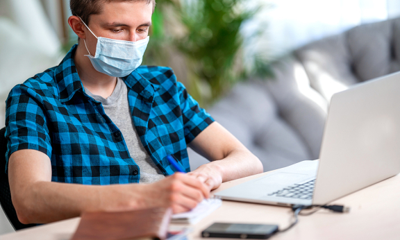 A student in a mask using a laptop