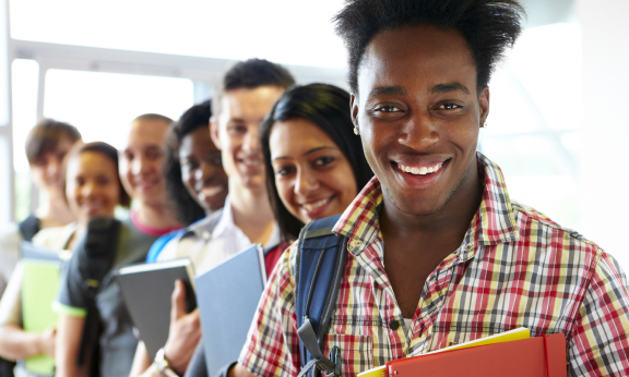 A group of students standing with their notebooks and smiling