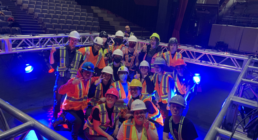People in hard hats and vests on stage