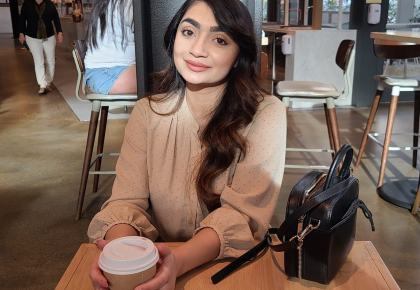 Henna Ahmad, Opticianry grad sits in a cafe with a cup of coffee