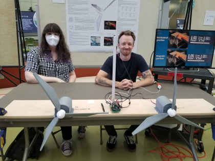 erin and cameron sitting at a table with electronic fans on display