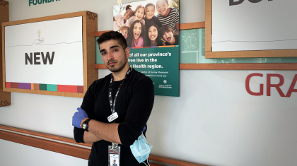 Psych Nursing grad Kaarun Sangra leans against a health care poster for the Surrey Hospital Foundation.