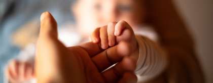 A baby's hand holding an adult's hand