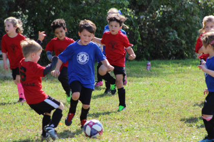 A group of kids playing soccer outdoor