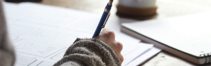 A hand holding a pen writing on papers