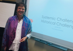 Woman smiling while presenting a slideshow.