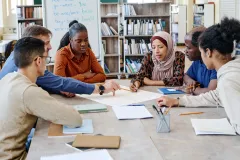 A group of diverse students working on a project around a table