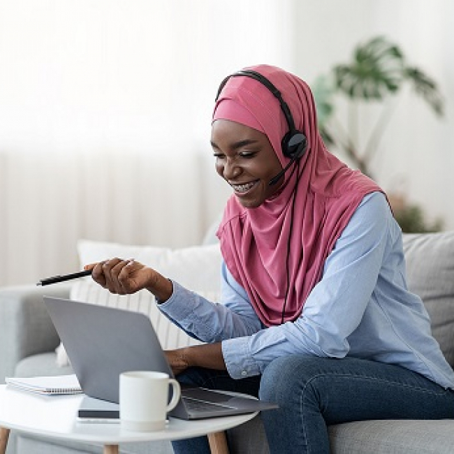 A student looking at her laptop and wearing headphones