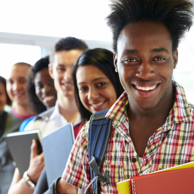 A group of students standing with their notebooks and smiling