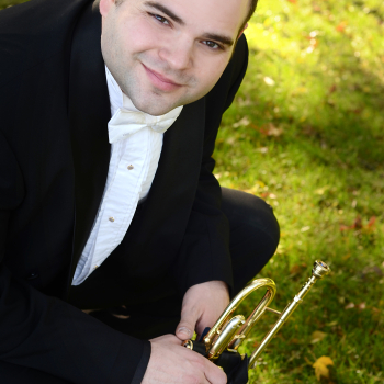 Photo of Mark D'Angelo with his trumpet with field of green grass in the background